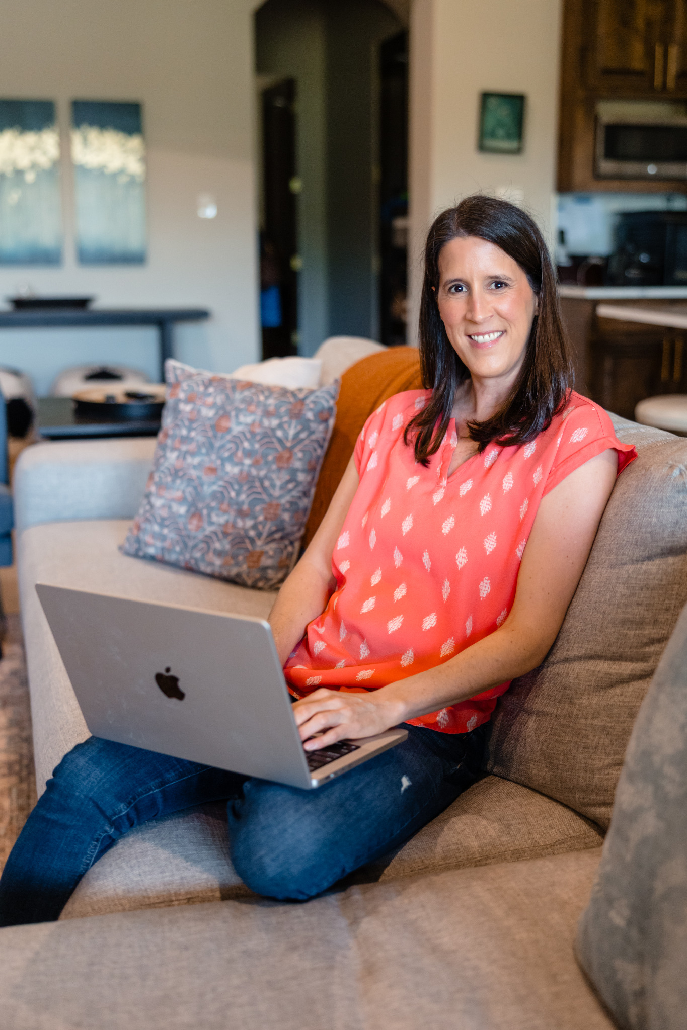 Katie sitting with her laptop in a comfortable living room.