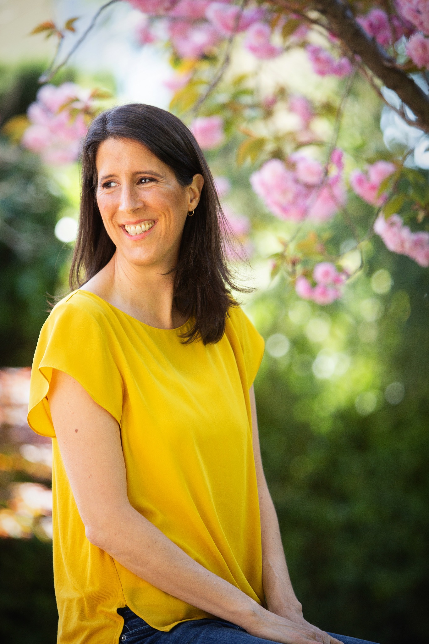 Katie outdoors beneath flowering branches.
